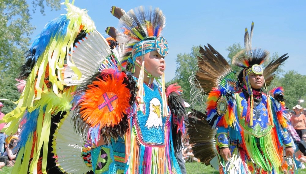 Aboriginal peoples are dancing wearing traditional costumes